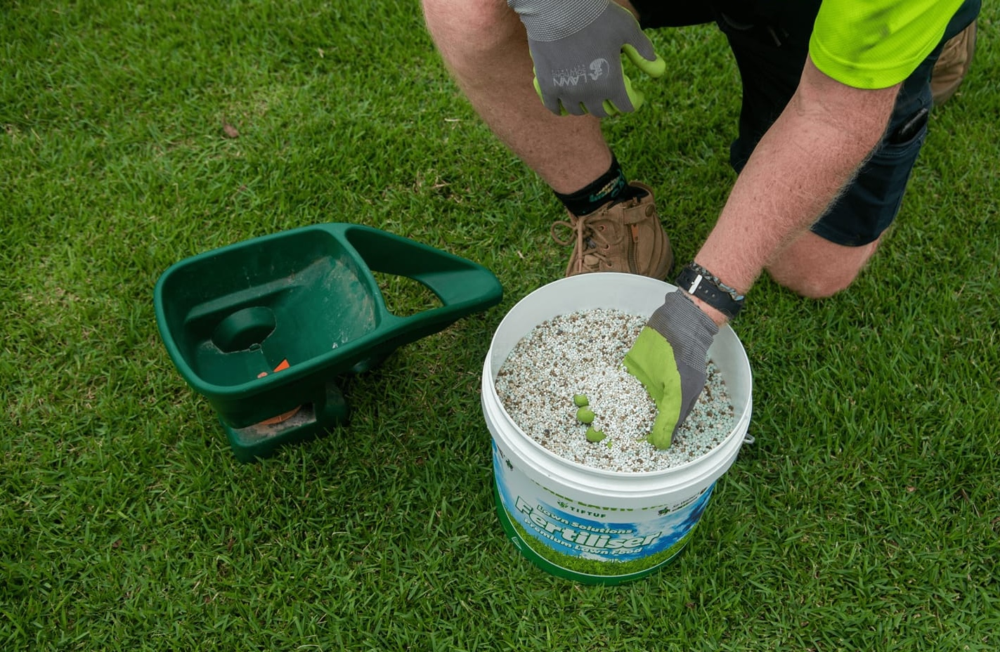Horticulturist applying organic fertiliser to native garden beds