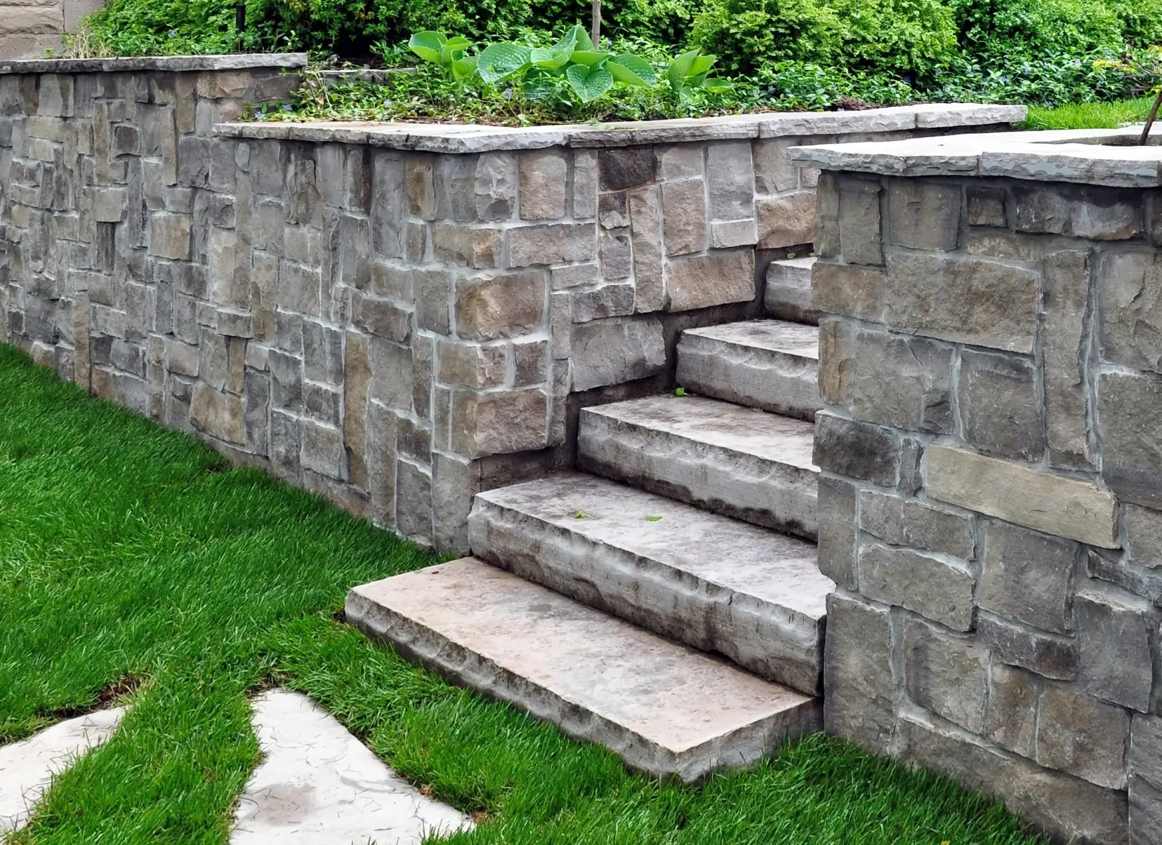 Construction of engineered block retaining wall with natural stone veneer